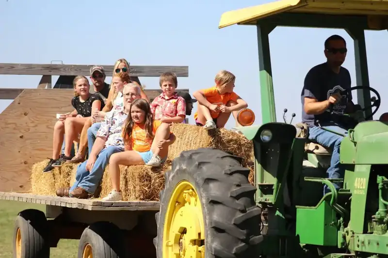 Families riding on straw bales behind the tractor
