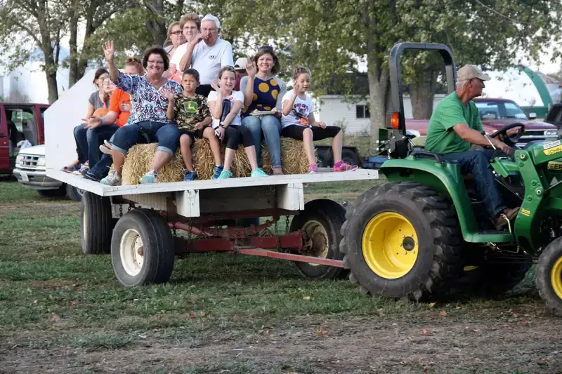 A wagon full of families waving on the hay ride